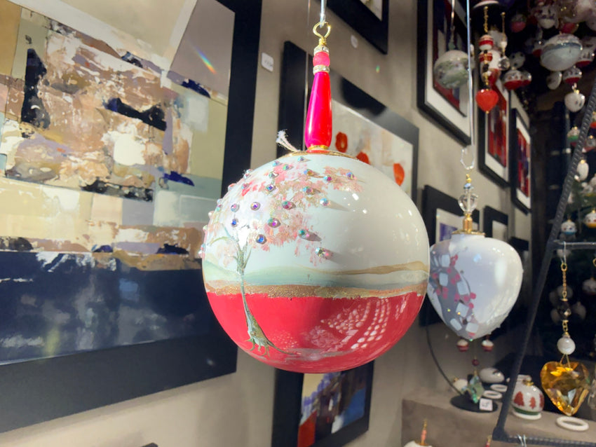 Boule en porcelaine au décor d’arbre rose, avec un dessous rose et des détails brillants.
